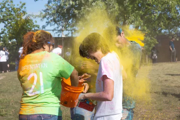 Two people tossing coloured chalk onto each other