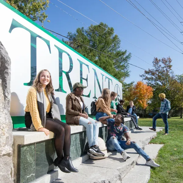 Students enjoying hot weather by the Trent main sign