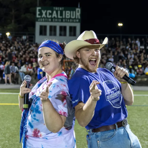 Two students standing back to back in front of crowd