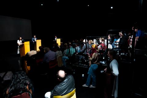 3 people speaking in front of a crowd