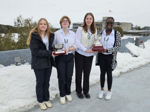 The winning team from the 2025 Peterborough Regional Ethics Bowl Tournament stand on the Faryon bridge holding their tropheys.