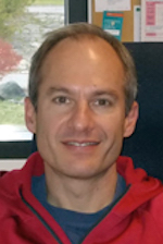 David Patton standing in front of a world map smiling