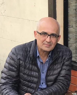 Professor Baban is sitting outside smiling to the camera