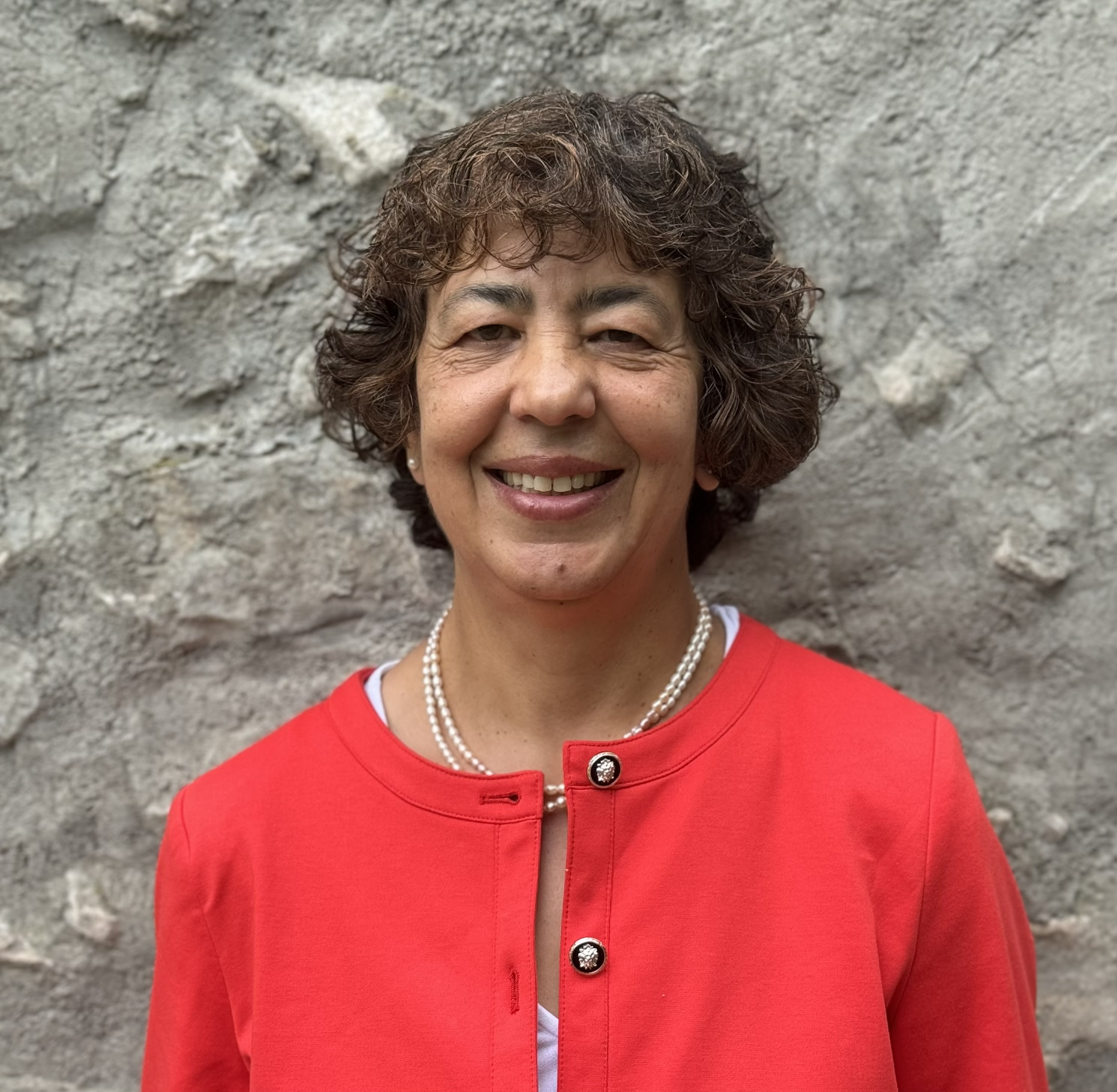 Professor standing in front of a stone wall smiling into the camera