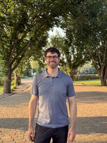 Professor standing on a pathway among trees