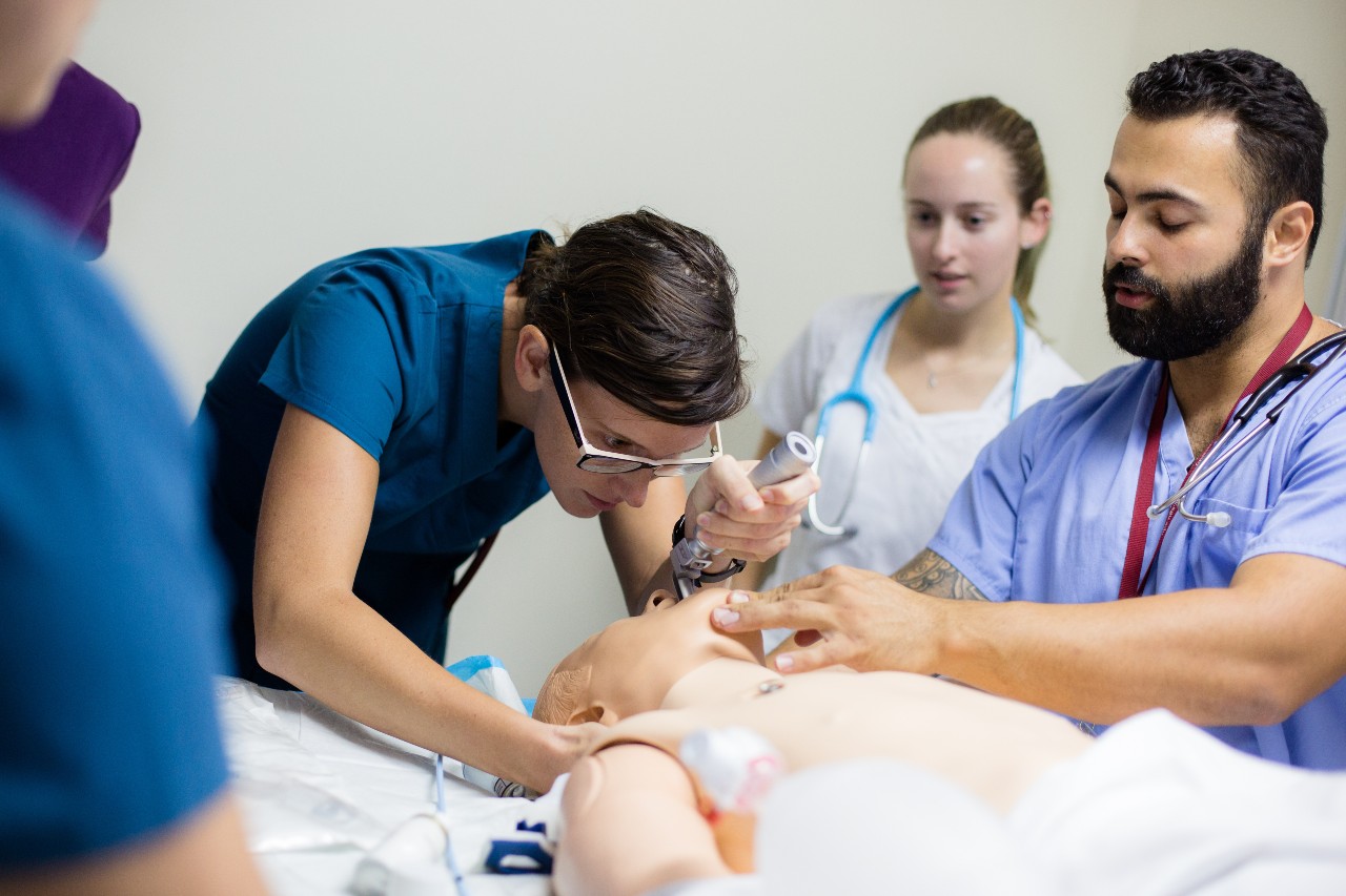 Medical students practicing on a dummy in a lab setting.