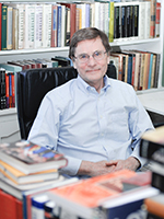 Dr. Leonard Connolly sitting in a chair smiling at the camera in his office.