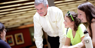 Dr. Leo Groarke talking at a table in the library with 3 students