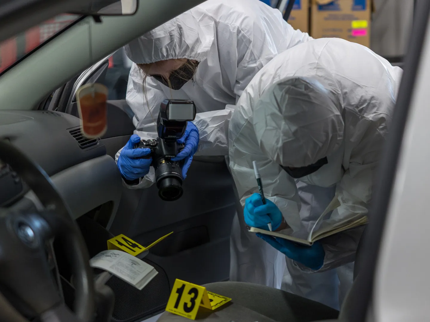Forensics science crime scene, student taking photos of evidence in car.