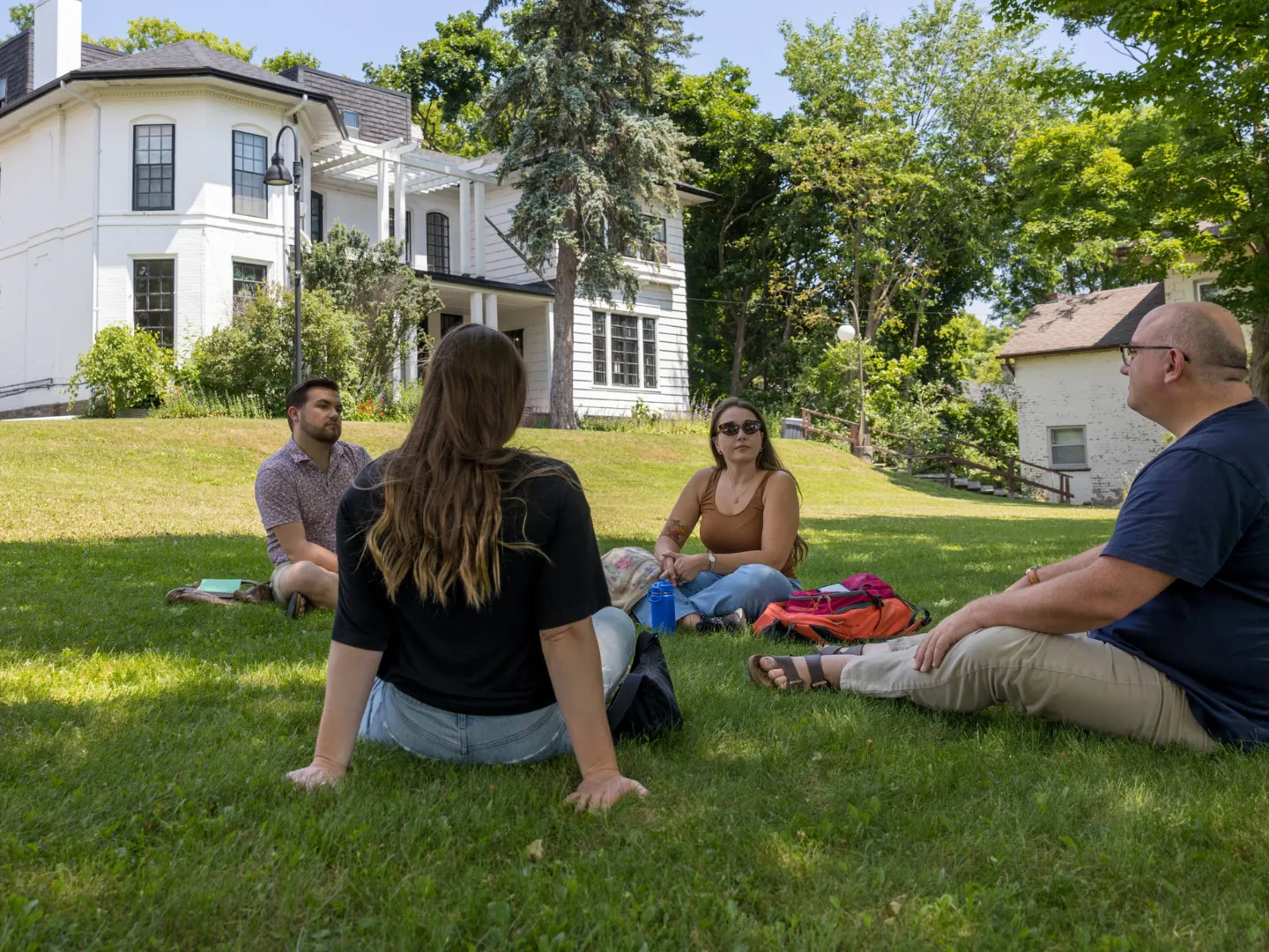 Group of graduate studies students talking outside of Scott House, Traill College.