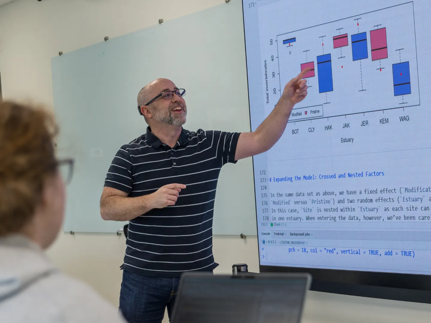 Wesley Burr teaching and pointing to math on screen in front of a class of students.