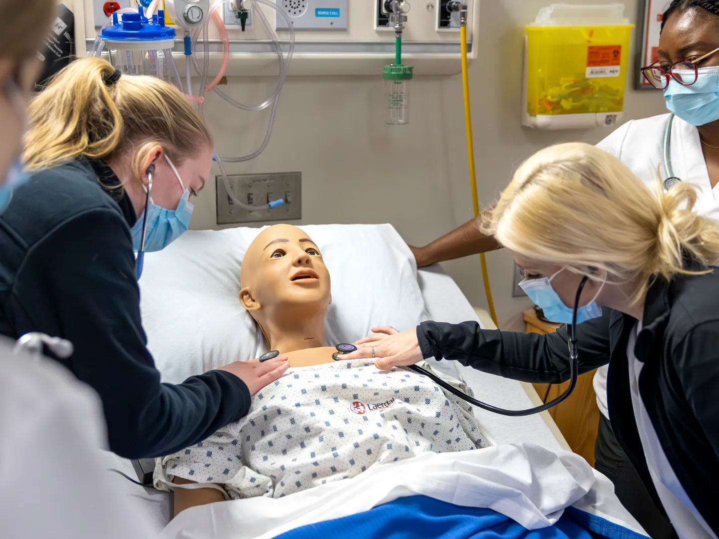Trent nursing students in Trent Simulation Hub checking the breathing of the simulation mannequin.