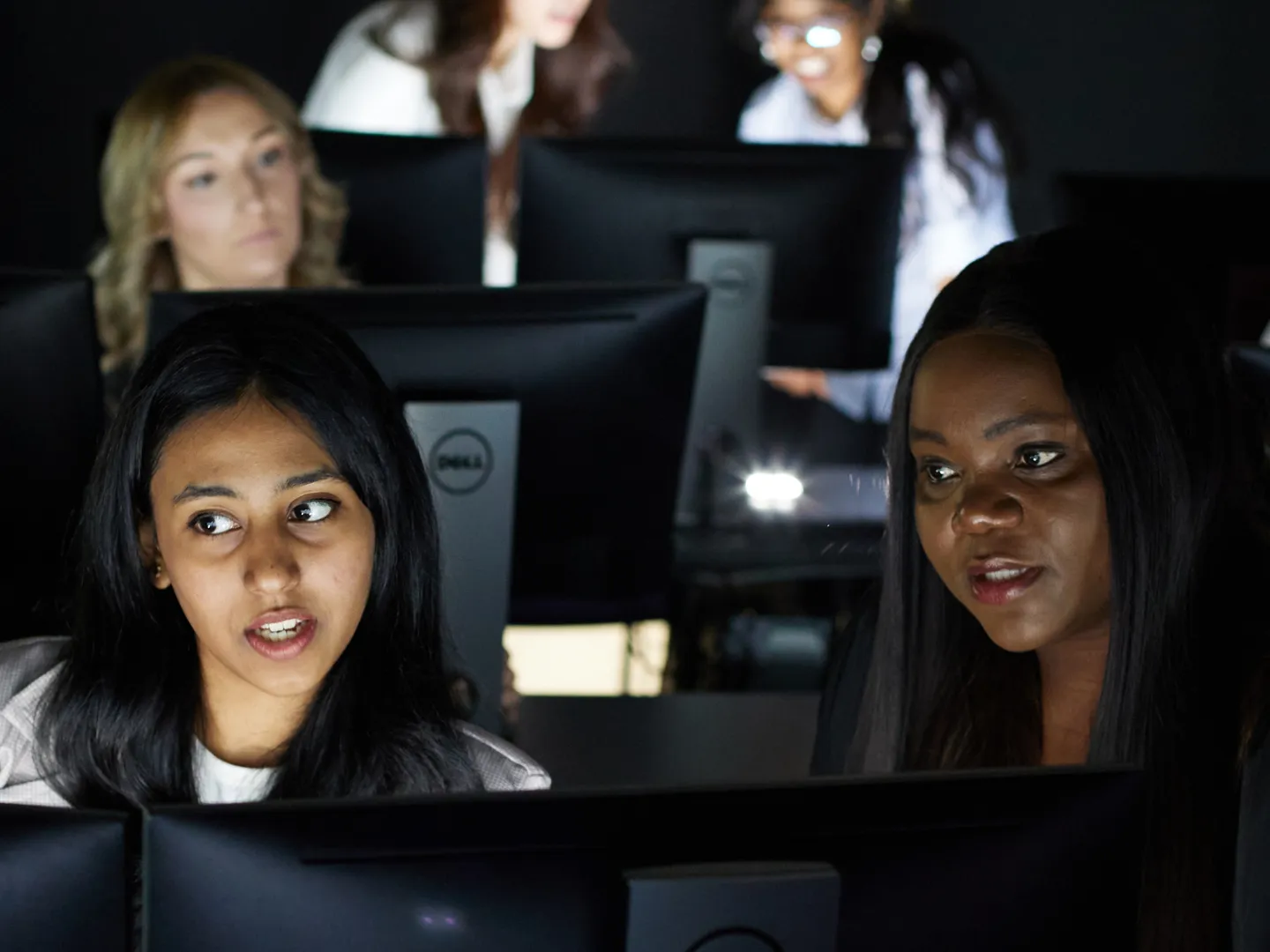 Two students talking and looking at a computer together.