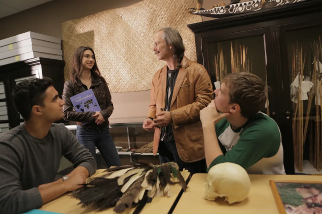 Anthropology students examine artifacts with their professor