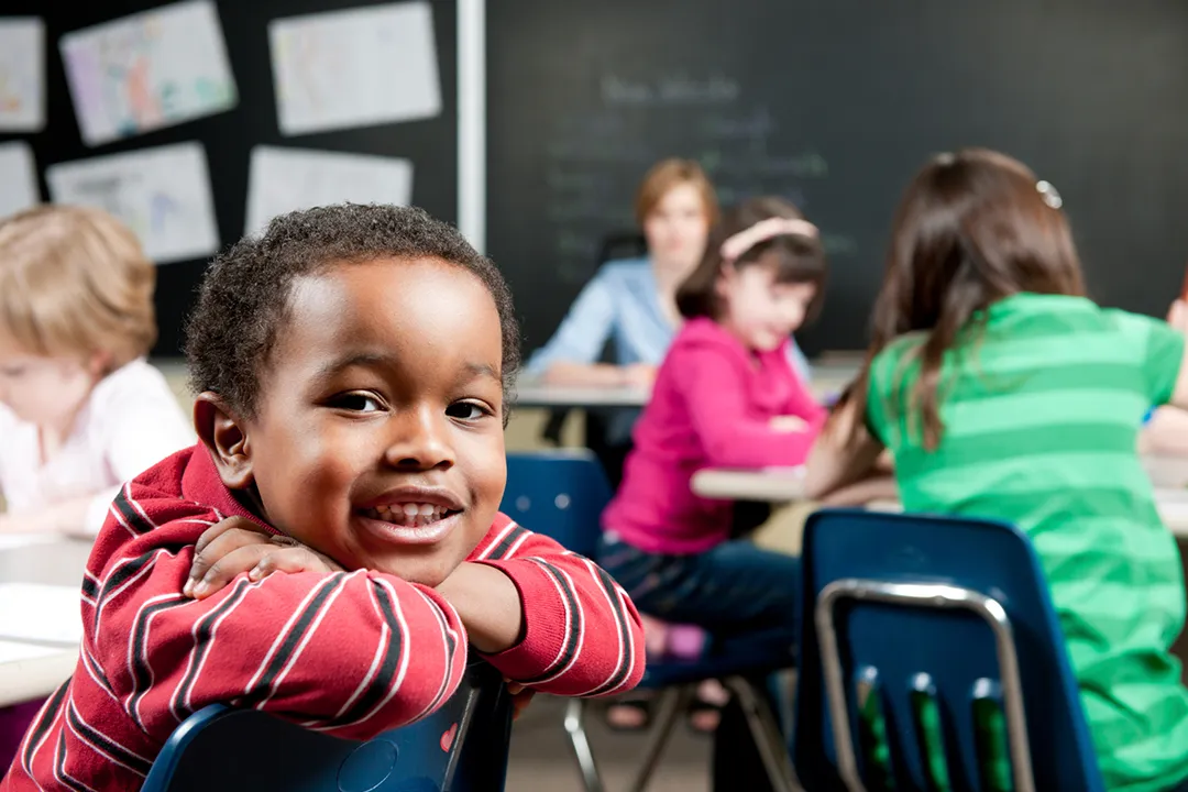 Child in classroom smiling at camera
