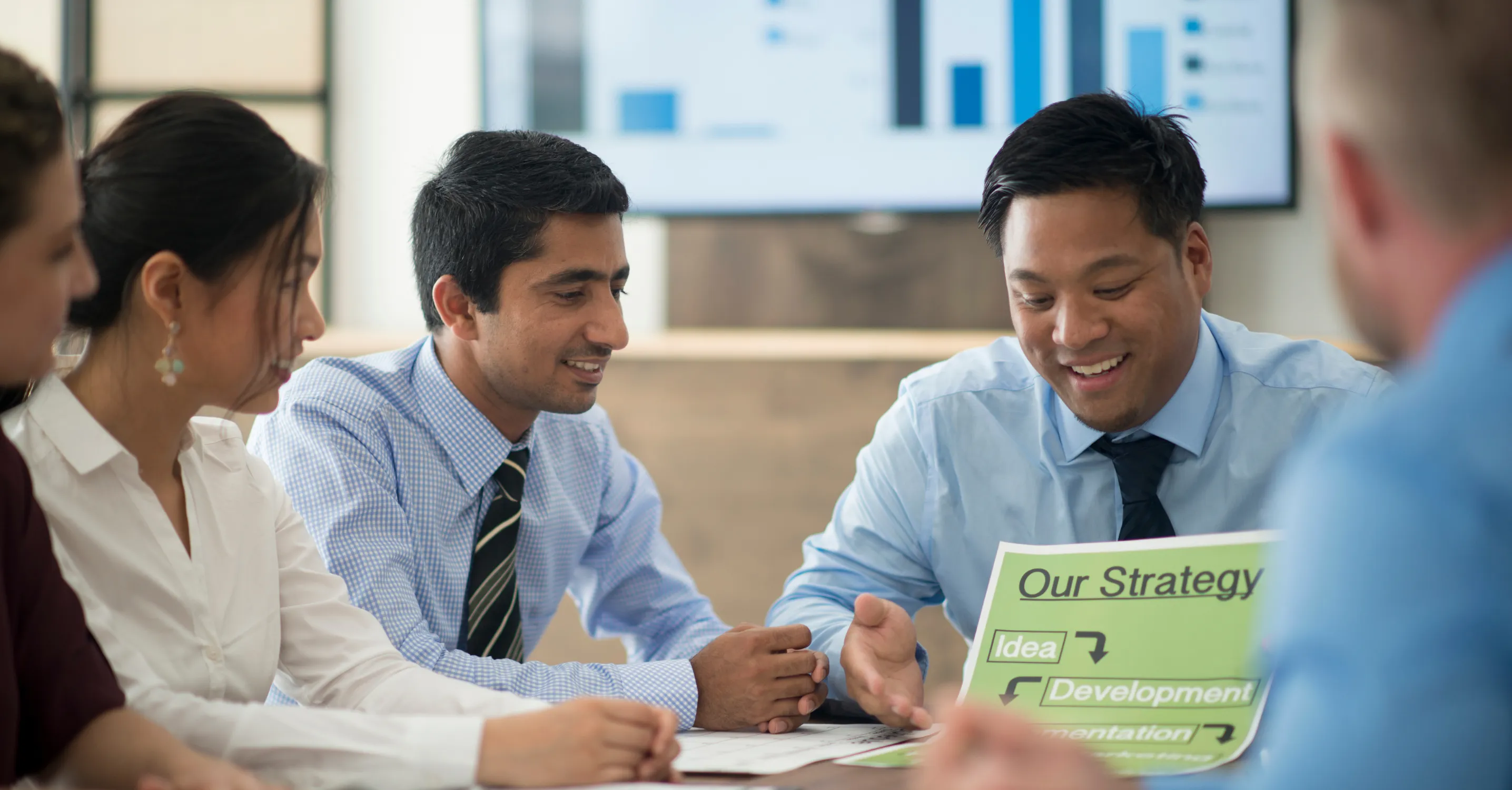 A group of business accountants in a meeting, talking and looking at papers.