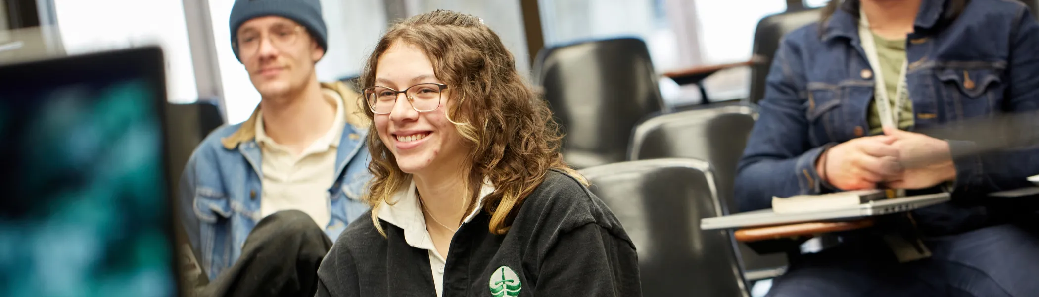 Trent University student in lecture, smiling towards the professor.