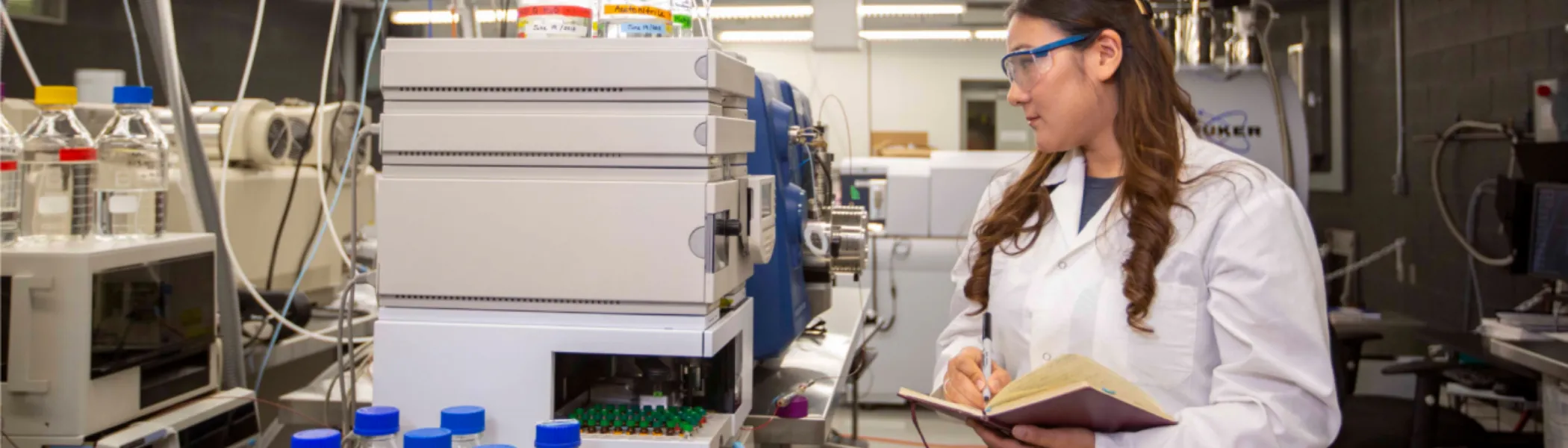 Student in lab, looking at equipment. 
