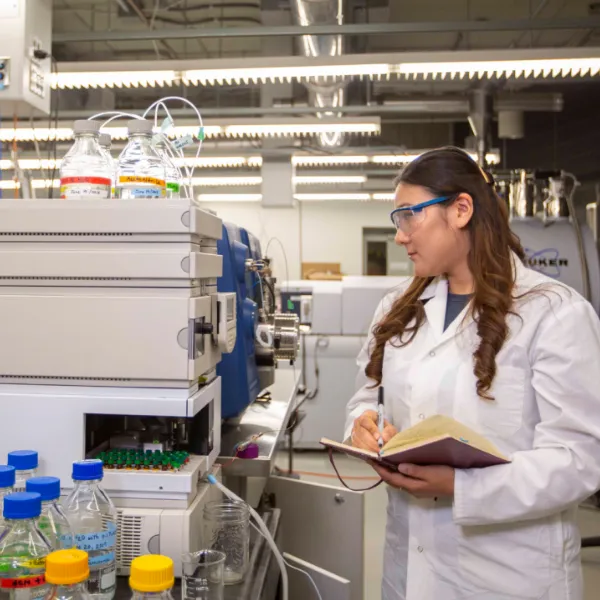Student in lab, looking at equipment. 