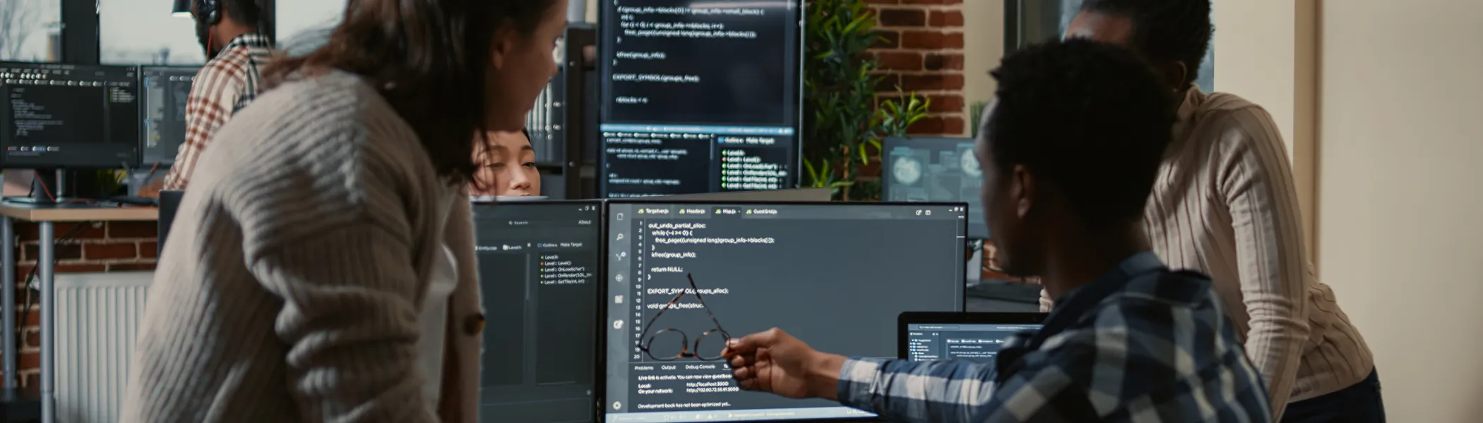 People sitting together, looking at a computer screen with code.