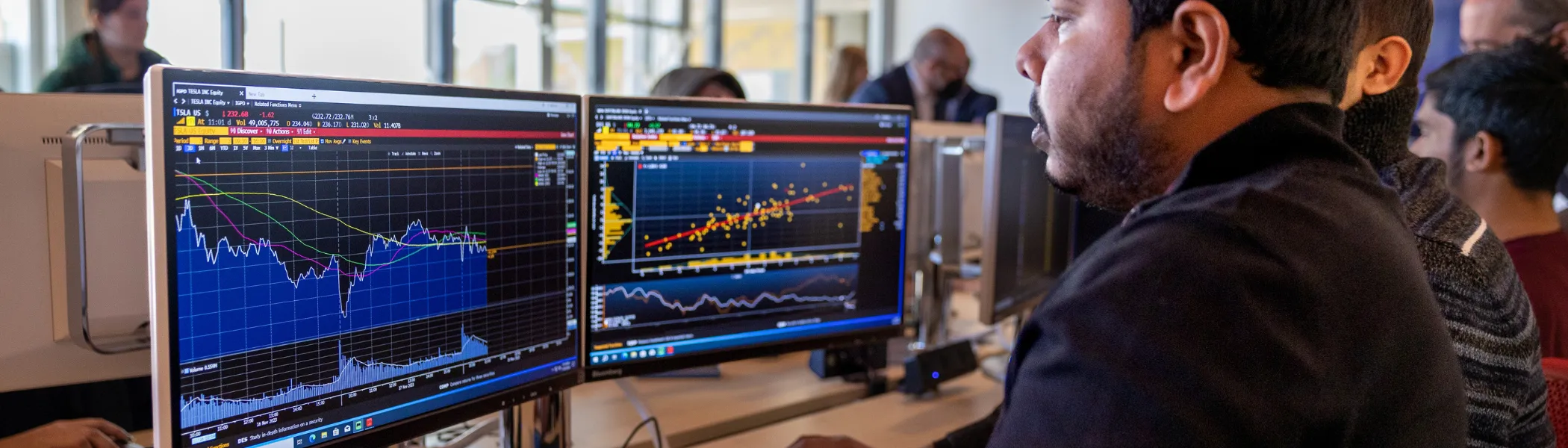 Trent University student in data science seminar, using computer that displays stocks.