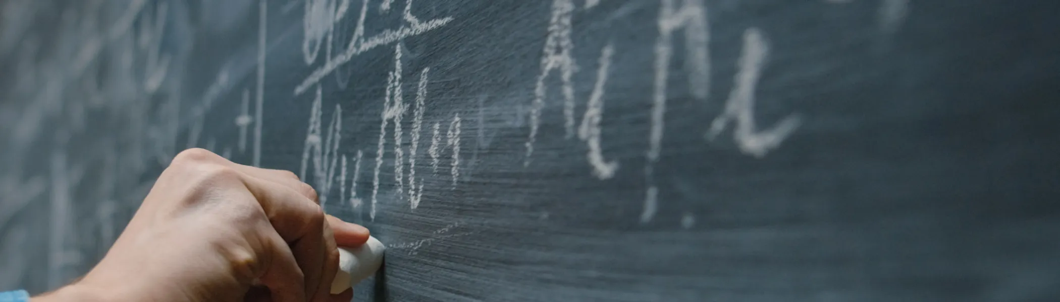 Mathematical physics equation being written on a chalk board.