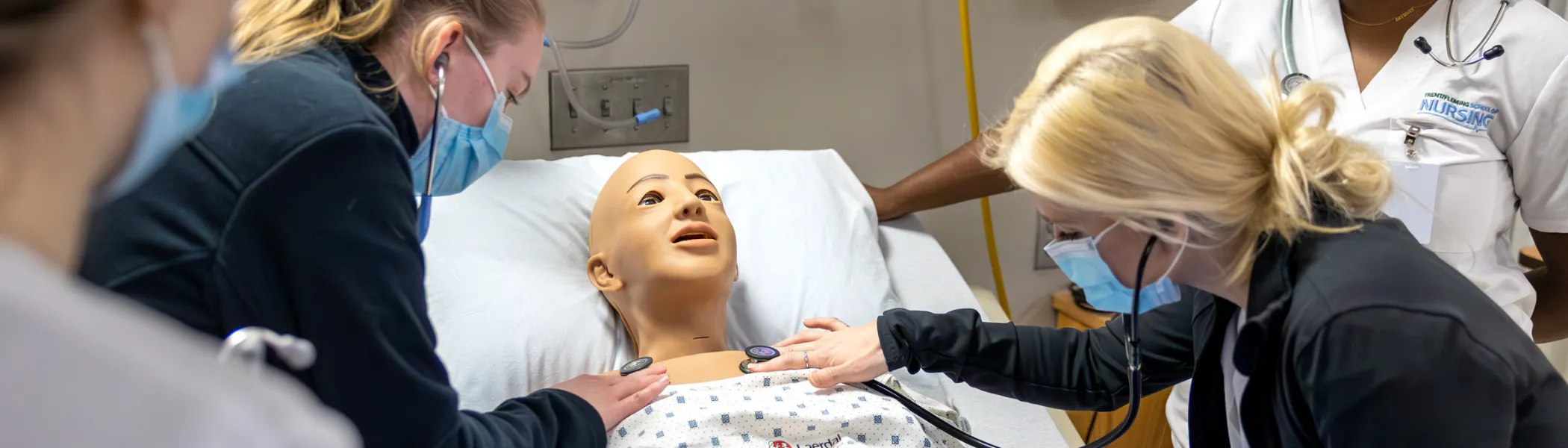 Trent University students in nursing lab, working together on doll.
