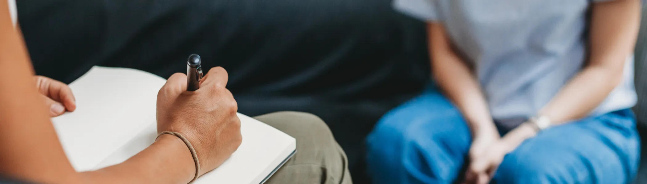 A therapist writing in a note book, while patience talks to them.