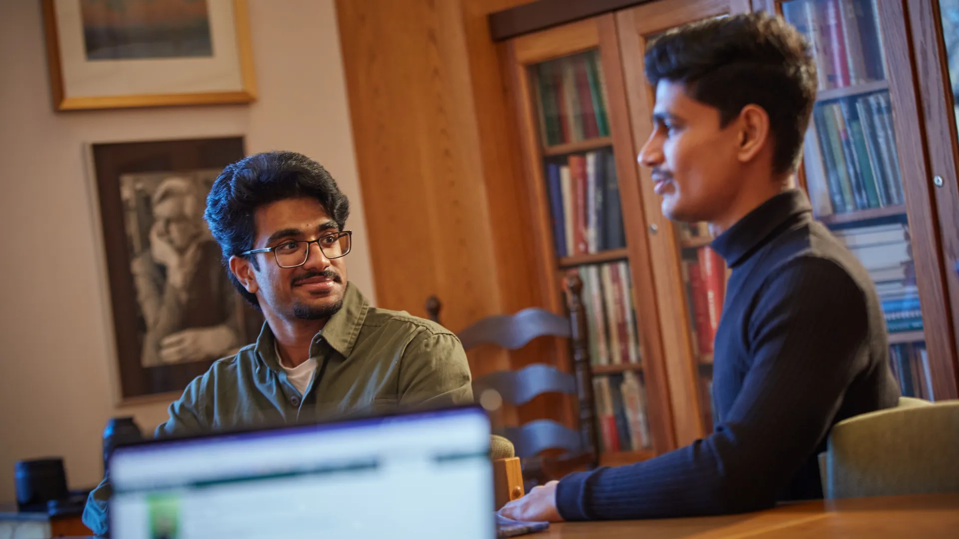 Two Trent University students sitting at a table, talking with each other.