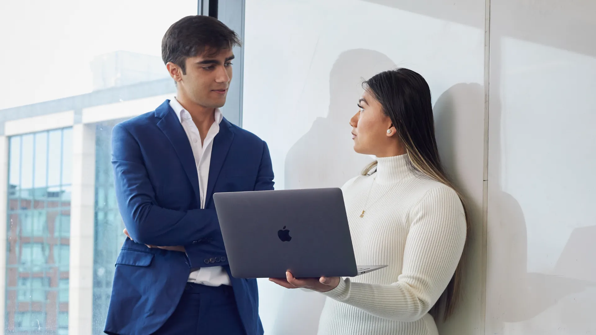 Two Trent University students at a business placement, talking together while looking at a computer.