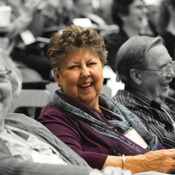 Older adults in lecture hall, one is smiling at the camera.