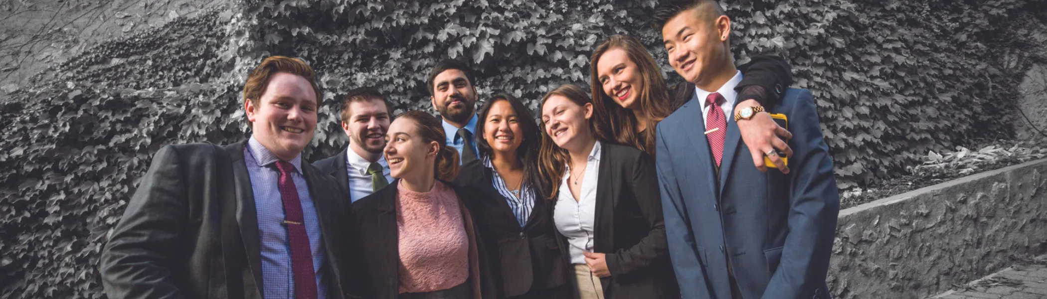 Group of Trent University students in business attire, laughing with each other.
