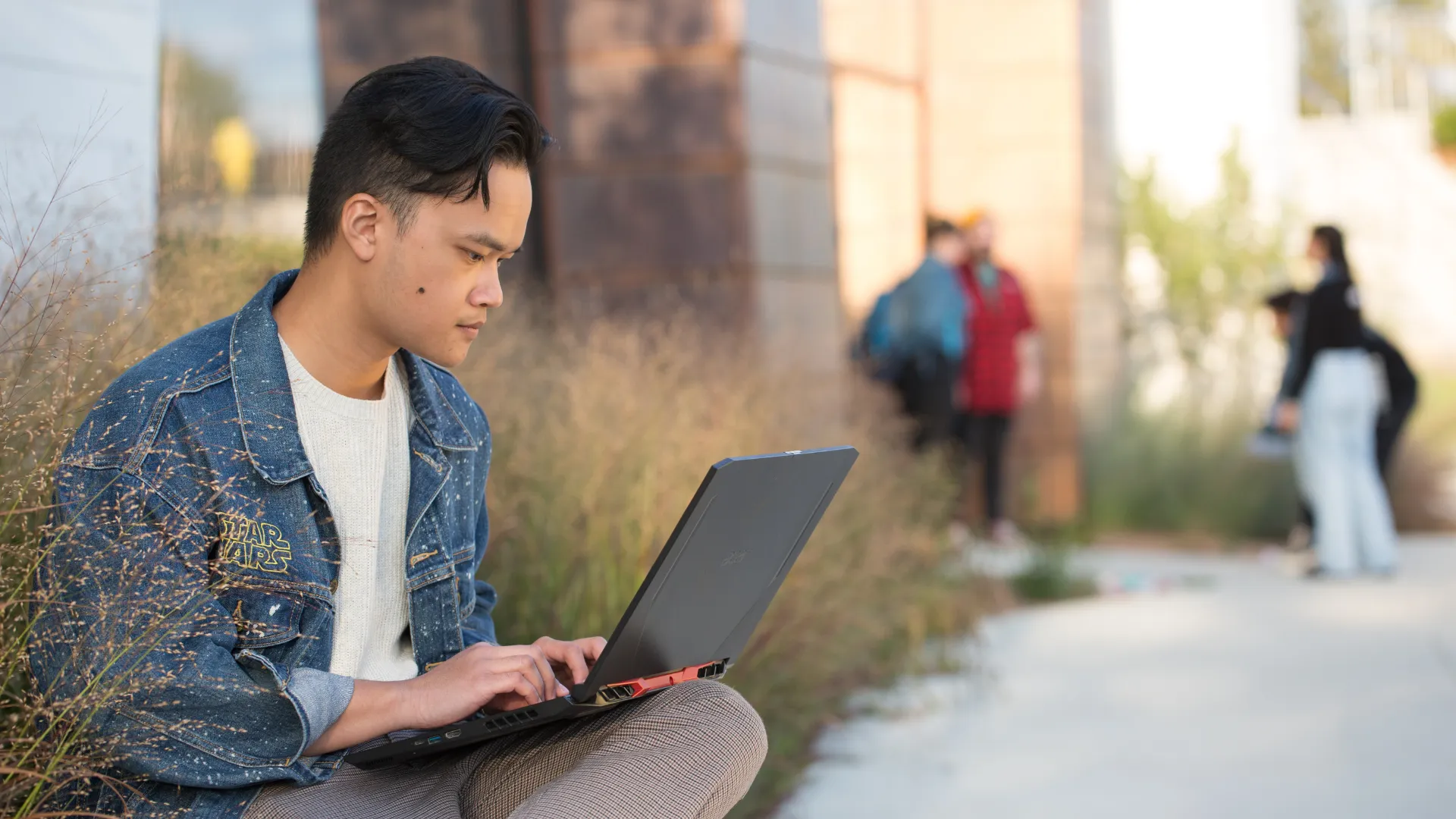 Trent University Durham student studying on laptop, sitting outside of building B.