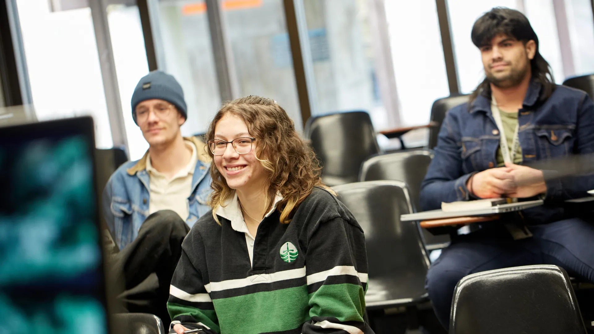 Three Trent University students sitting and listening to professor in lecture.