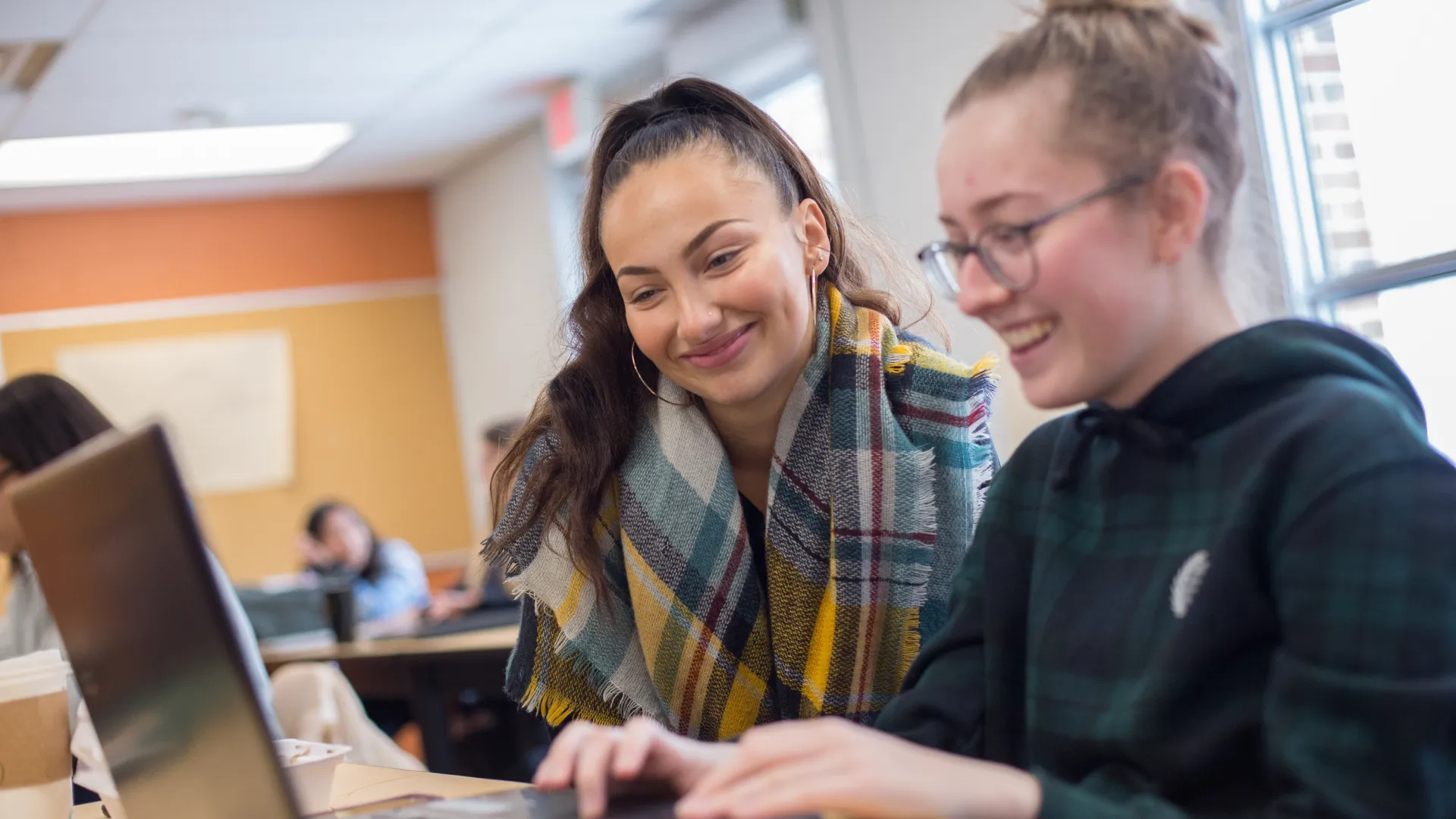 Two Trent University students, working together on a laptop in class.