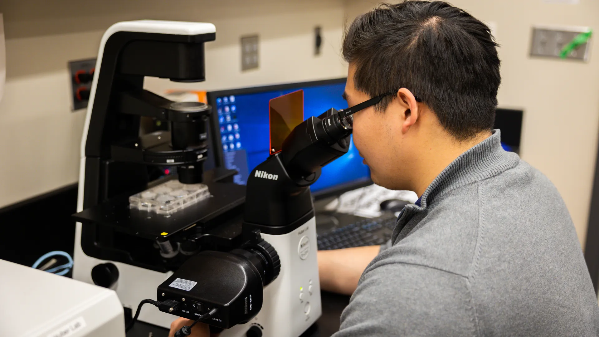 A Trent University student looking through microscope in lap.