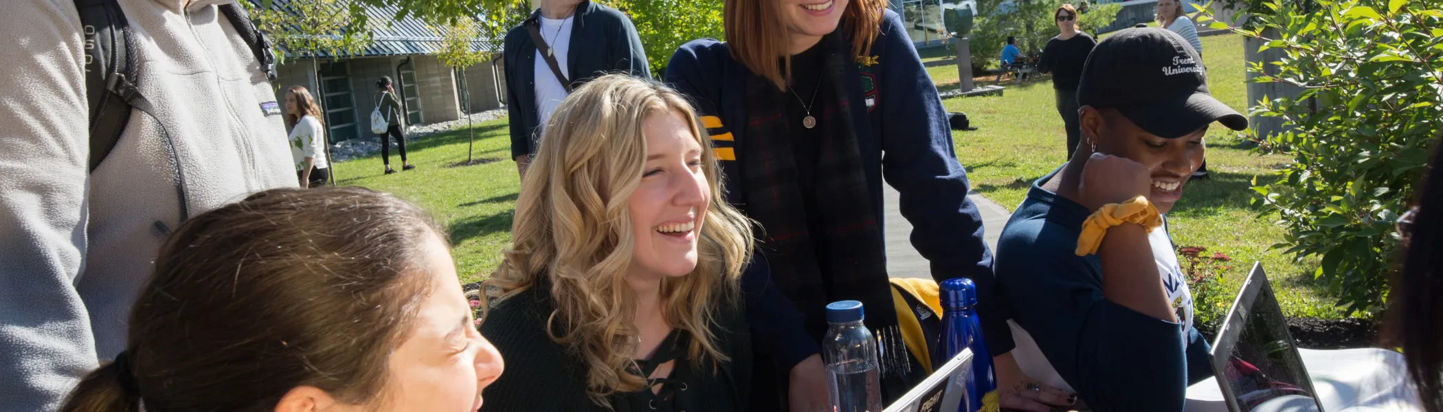 A group of Trent University students, working together on their laptops and talking.