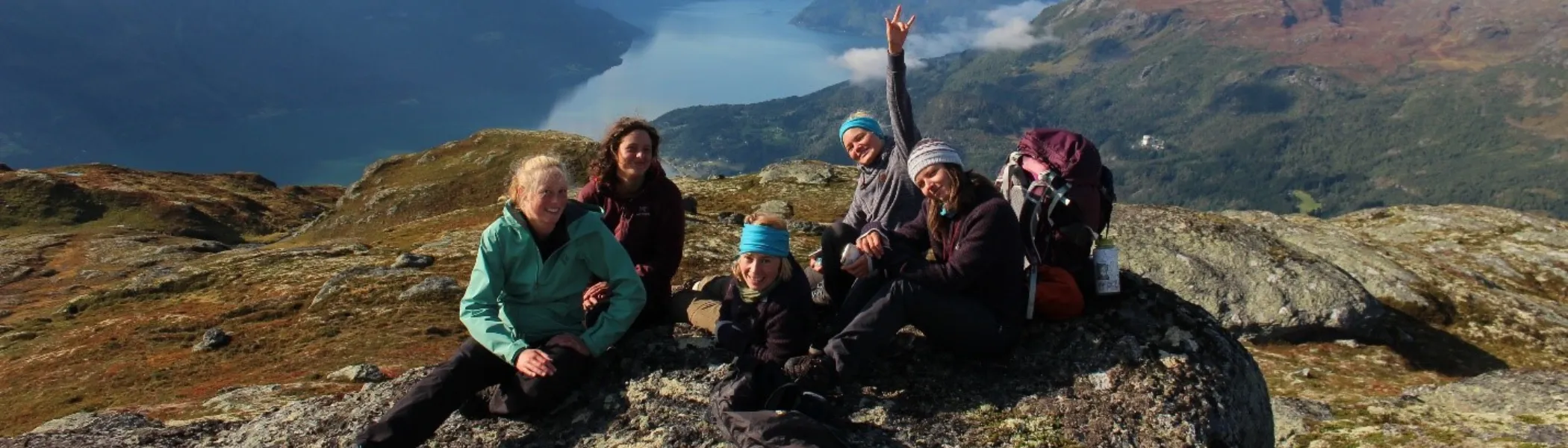 Trent University students on a study abroad program, sitting on top of a mountain, smiling at the camera.