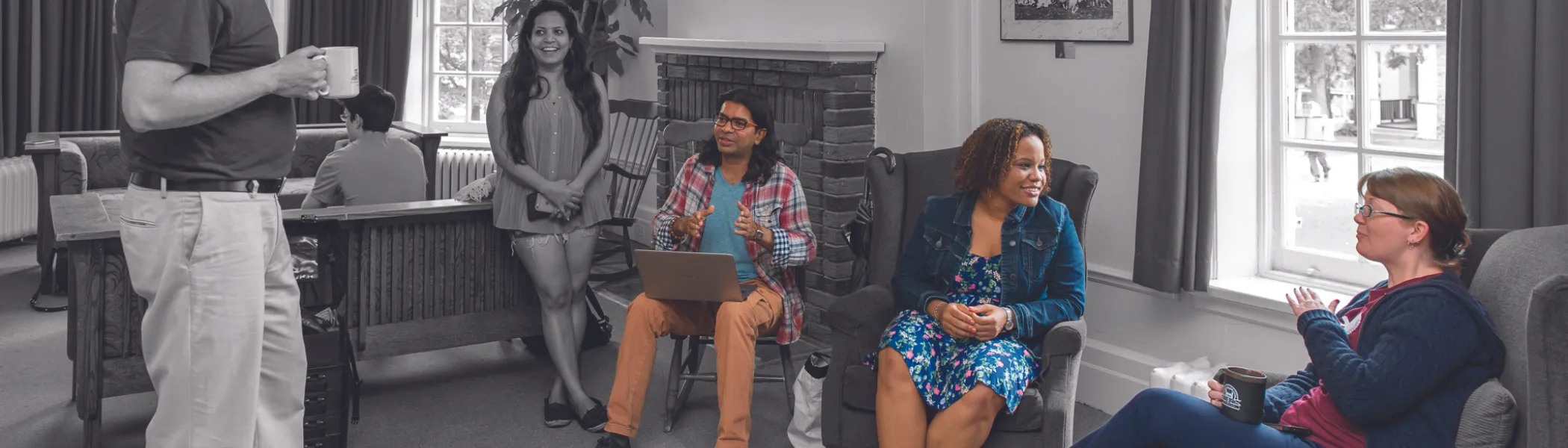 A group of Trent University students and staff, talking in common room.