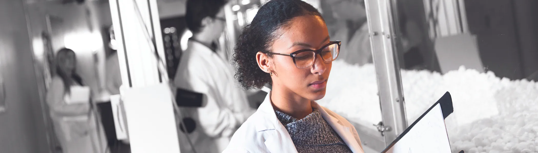 A Trent University student looking at a clip board, in a lab.