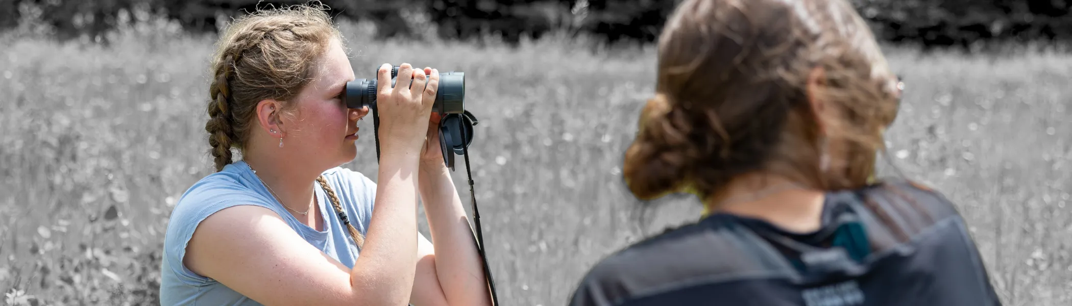 Trent University students surveying land with binoculars.