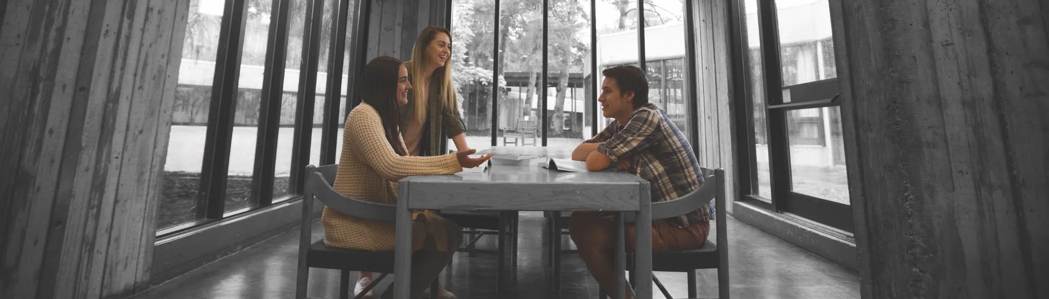 Trent University students sitting at a table, talking with each other.