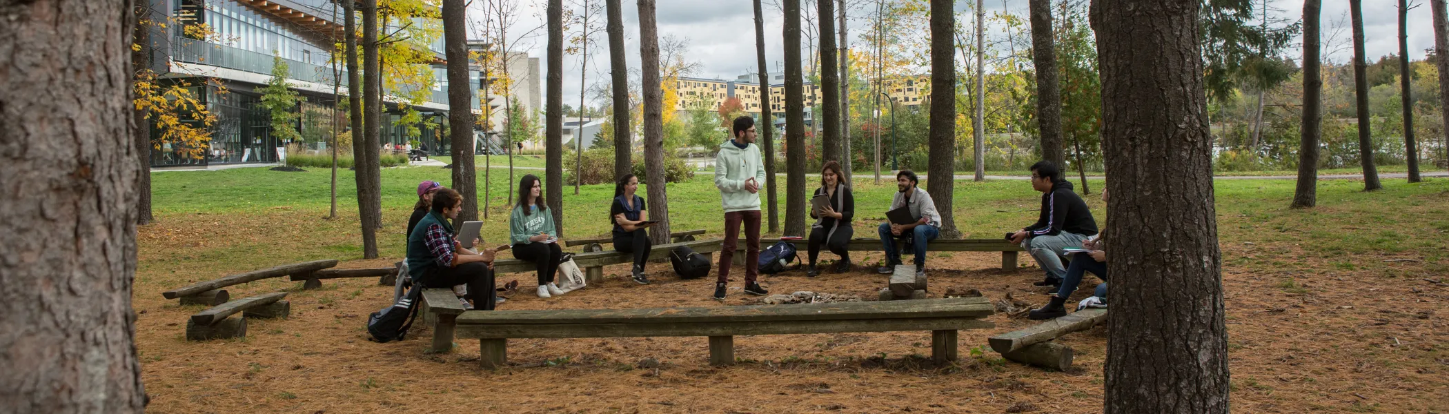 Trent University students giving a presentation outside in forest.