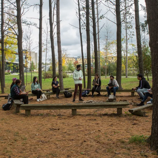 Trent University students giving a presentation outside in forest.