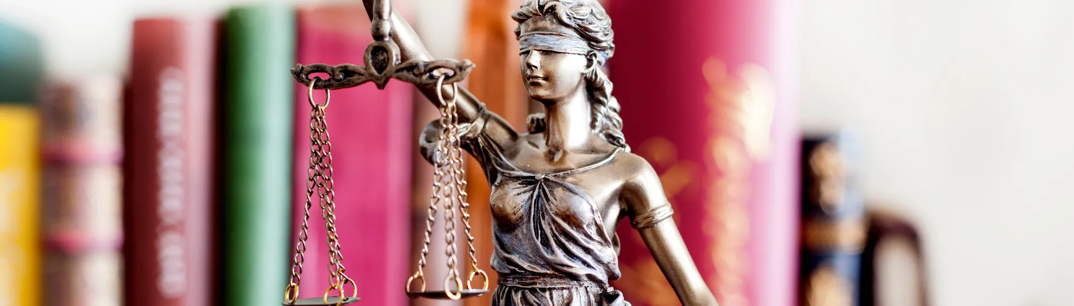 Statue of Lady Justice in front of books.