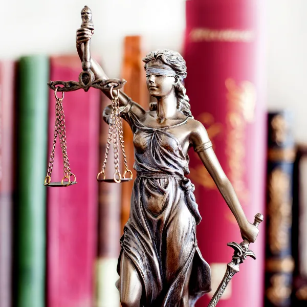 Statue of Lady Justice in front of books.