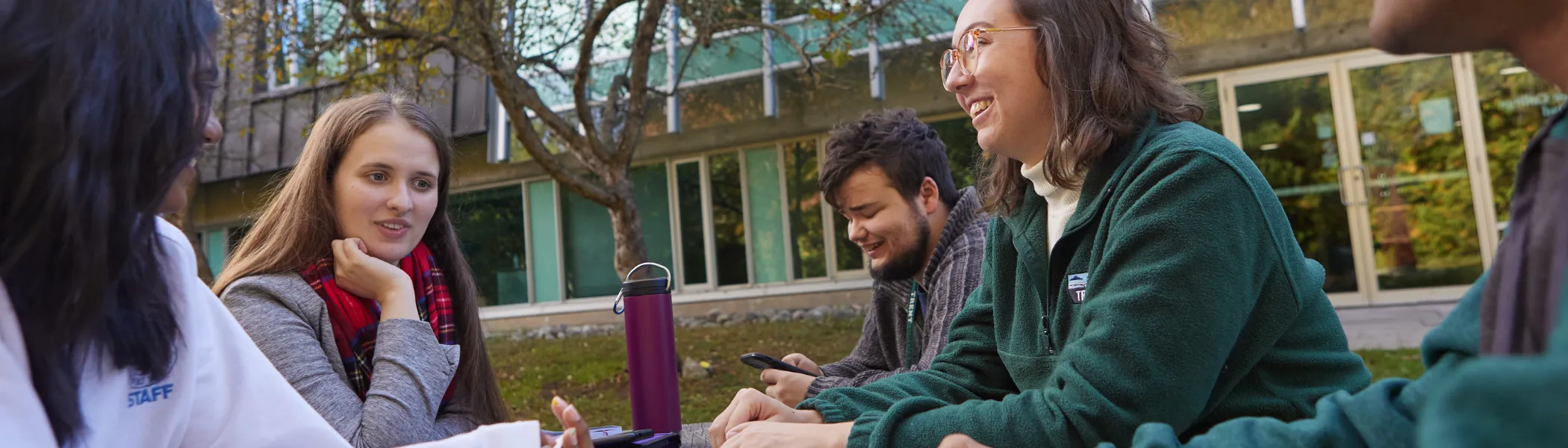 Trent University students sitting on a beach, studying and talking.