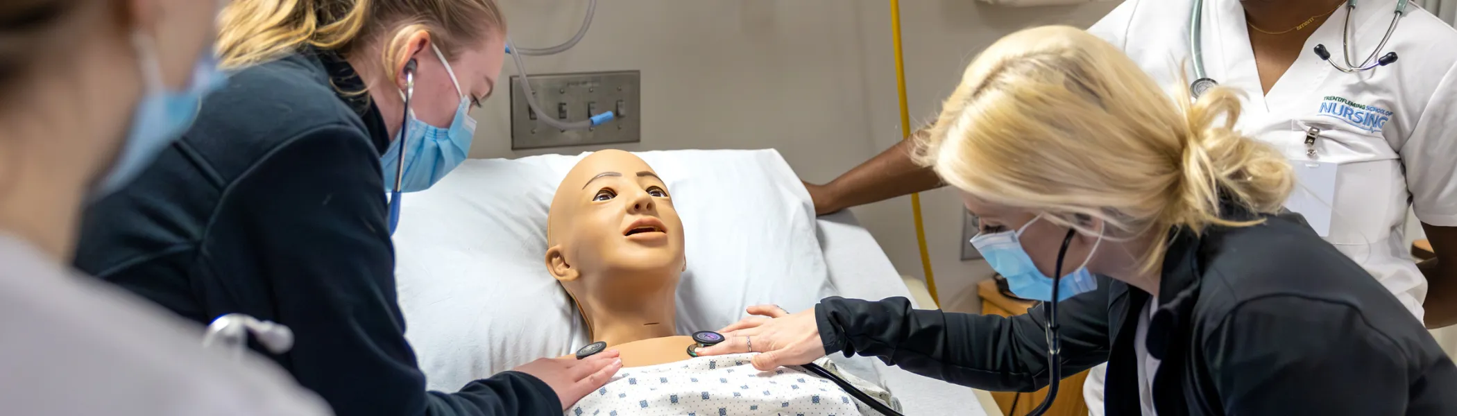 Trent University nursing students using medical doll to hear heart beat.