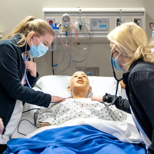 Trent University nursing students using medical doll to hear heart beat.