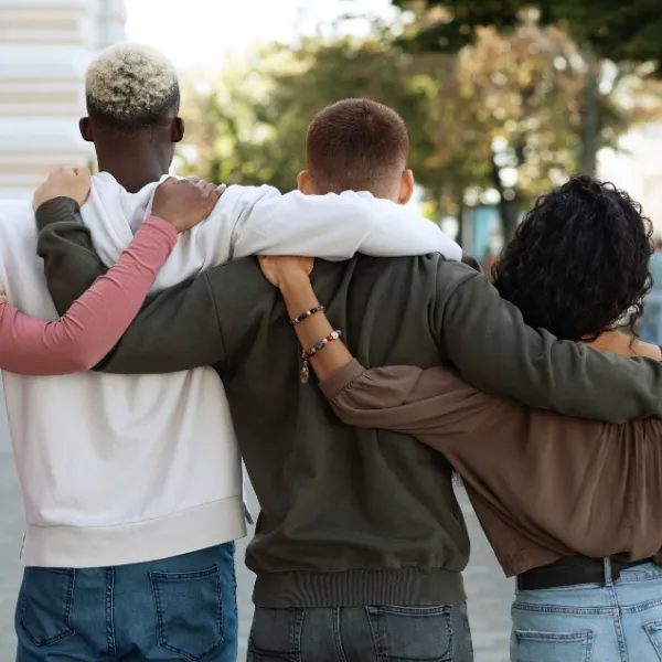 Back view of group of people arms on each other backs, walking down street.